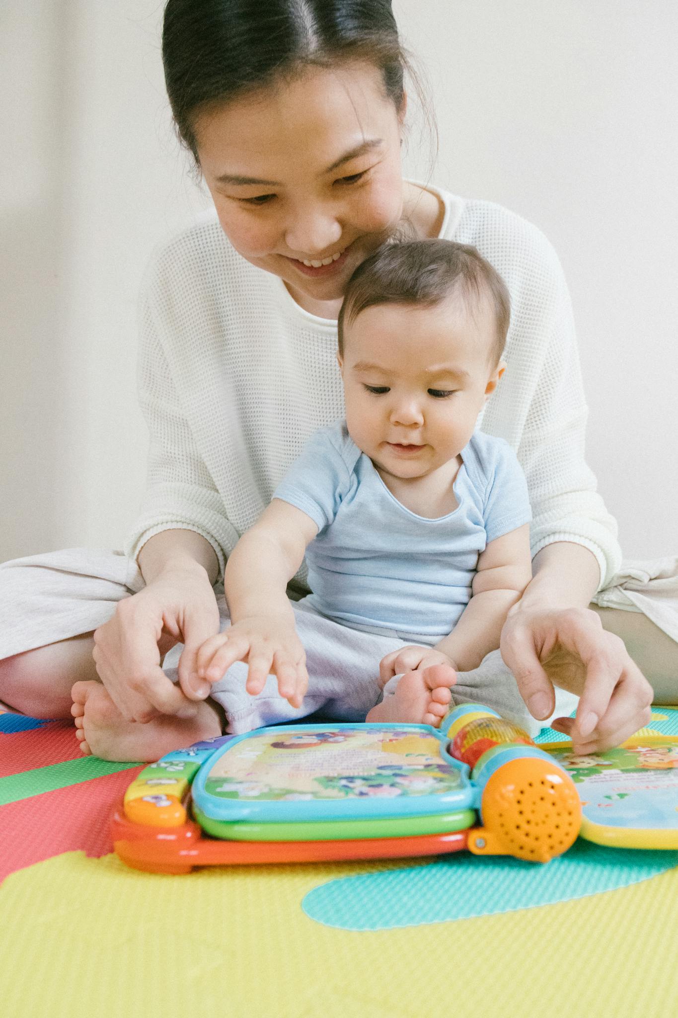 A happy mother and baby enjoy playtime with a colorful educational toy, fostering learning.