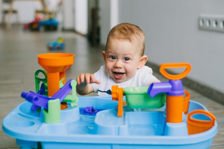 A joyful baby enjoying playtime with a colorful water toy indoors, showcasing fun and curiosity.