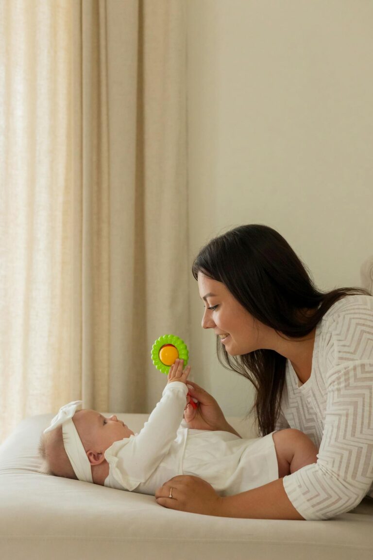 A mother and her baby joyfully interacting with a colorful toy indoors.