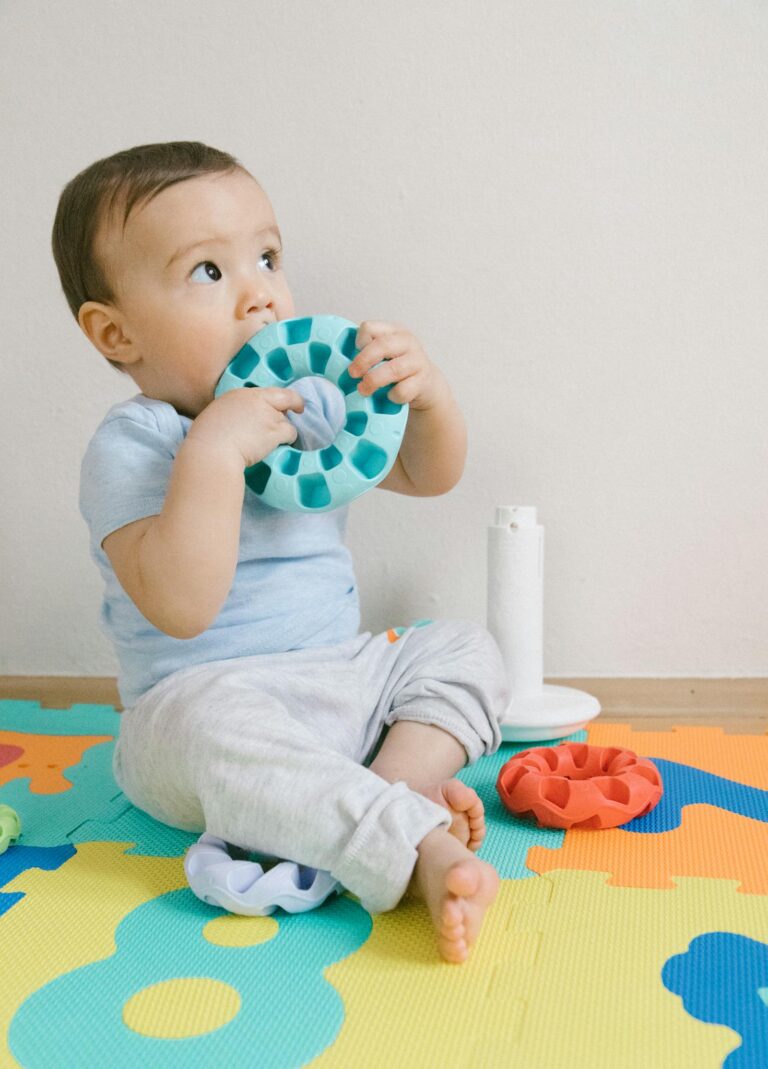 Charming baby in Dubai playing with toys on a puzzle mat, showcasing curiosity and joy indoors.